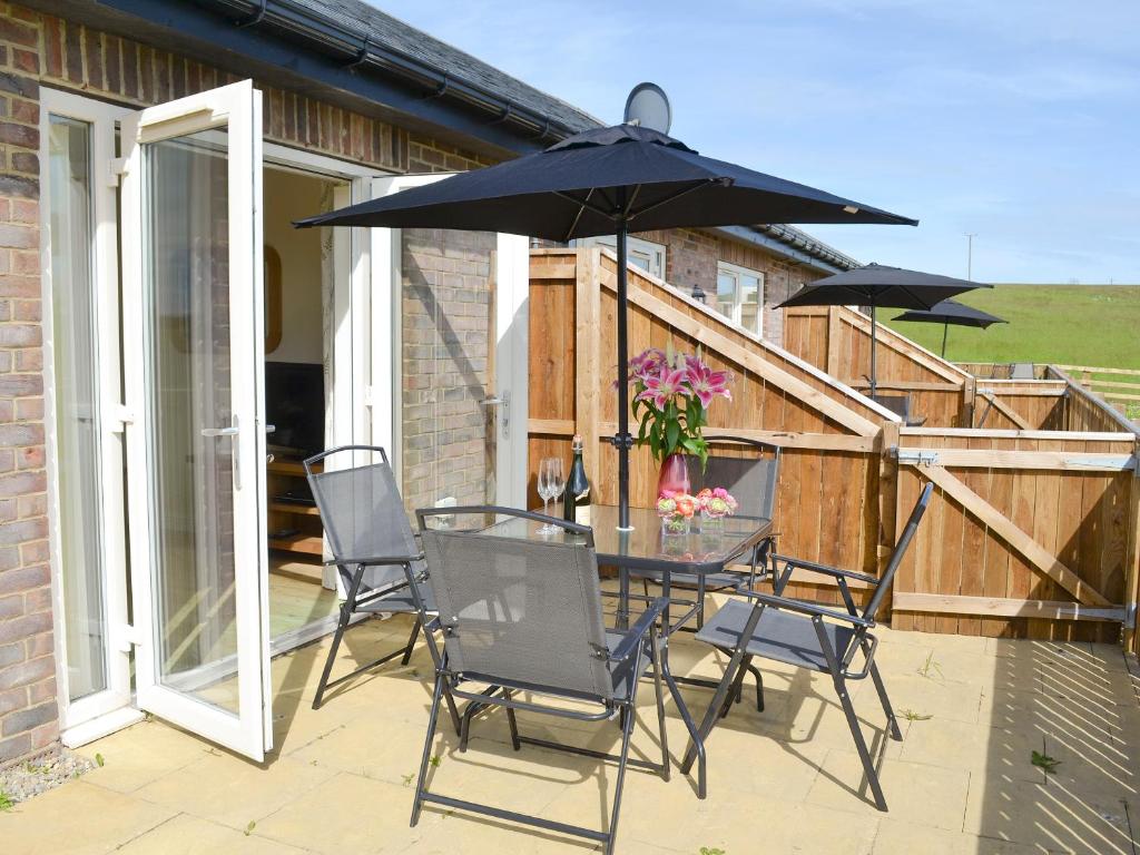 a patio with a table and chairs and an umbrella at Kestral Cottage in Shotton