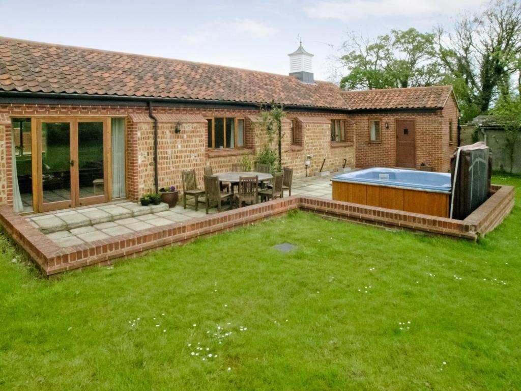 a garden with a patio and a swimming pool at Beech Barn in Horning