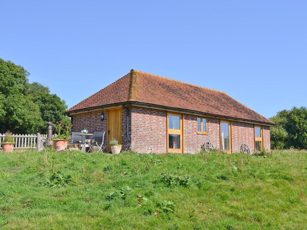 a small brick house in a field of grass at Coblye Barn in Brightling