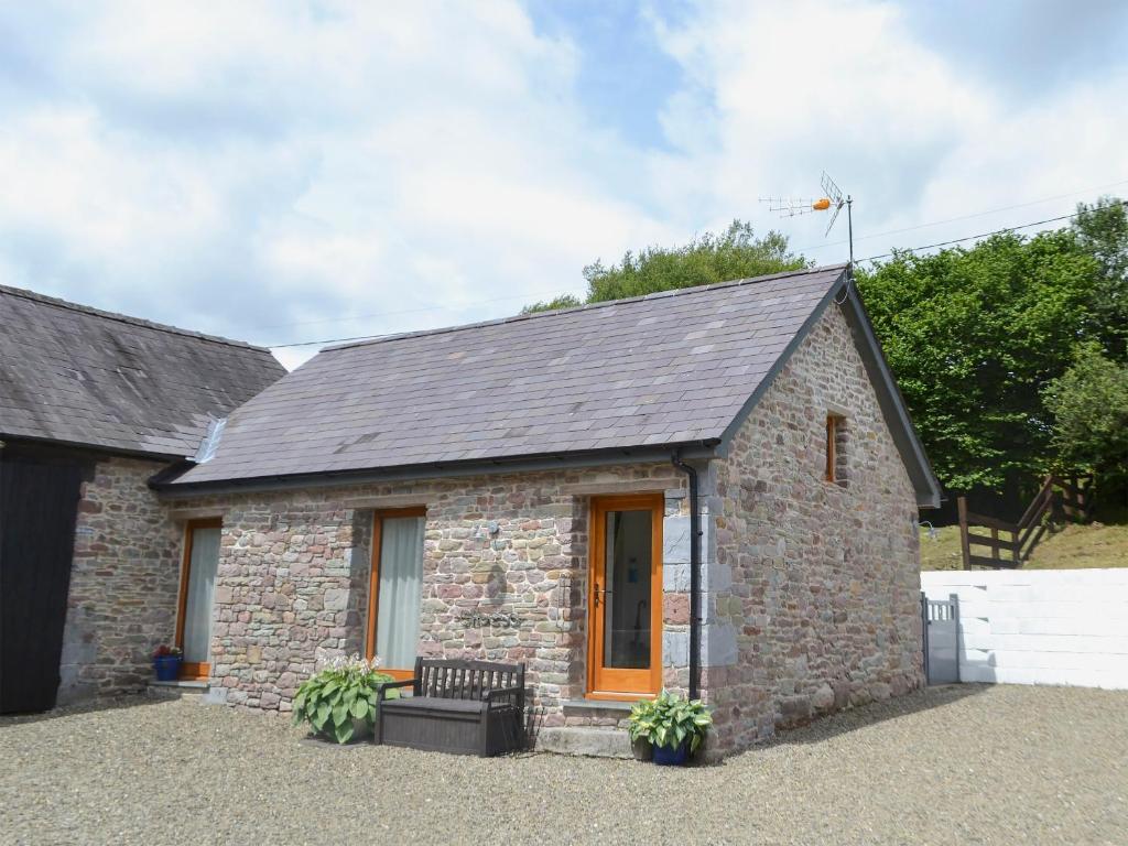 a small brick house with a black roof at Bramble Cottage Mountain Retreat in Twyn Llanan