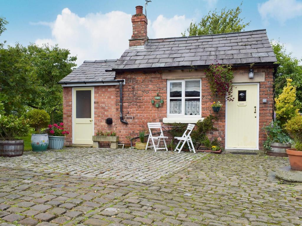 a brick house with two chairs and a patio at The Dairy in Burscough