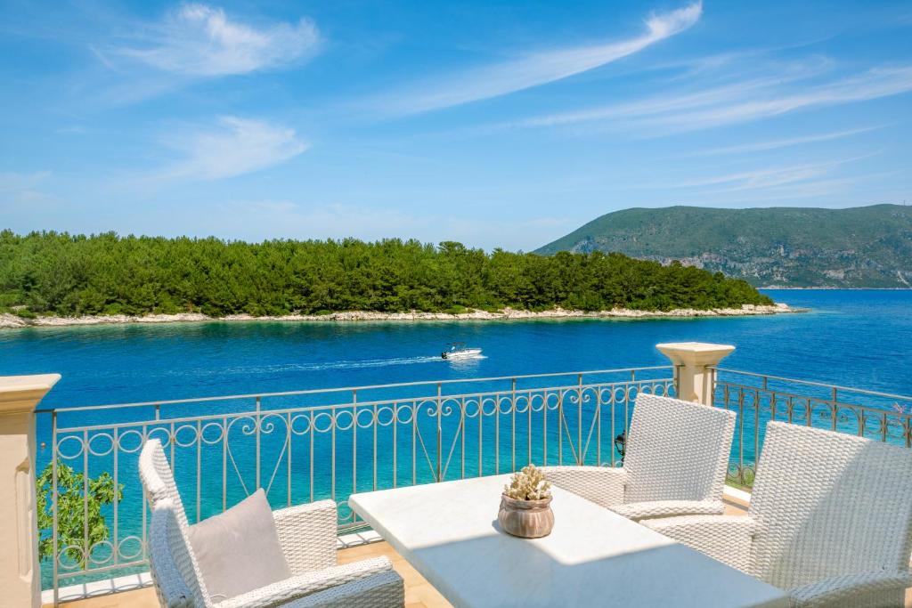 een balkon met een tafel en stoelen en de oceaan bij Captain's Quarters at Fiscardo Waterfront-feel the breeze in Fiskardho