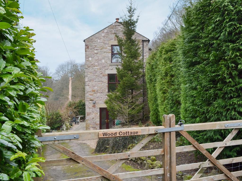 an old house with a wooden gate in front of it at Wood Cottage in Whaley Bridge