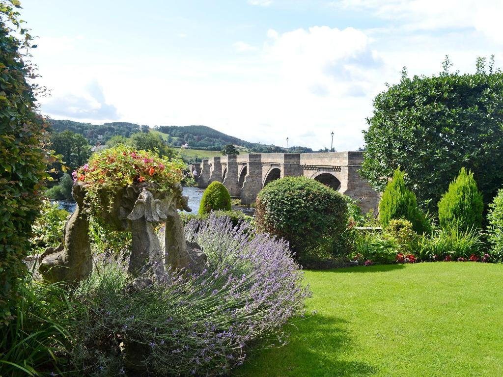 a garden with flowers and a bridge in the background at Quince Cottage - 25625 in Corbridge