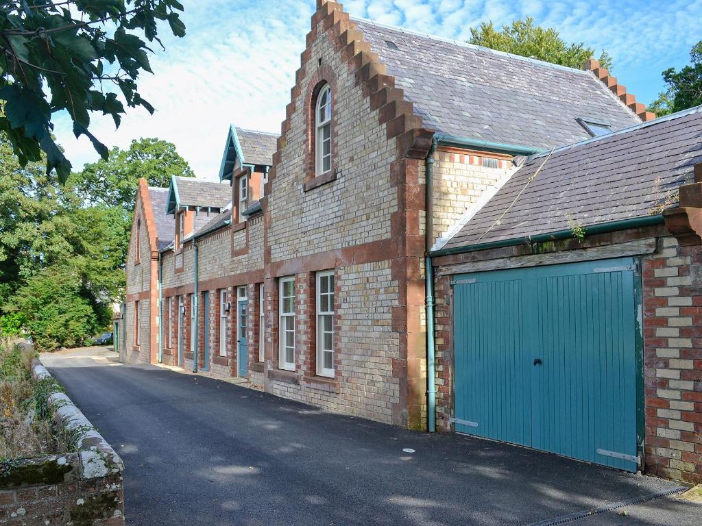 a brick building with a garage with a blue door at Two The Stables in Dalrymple