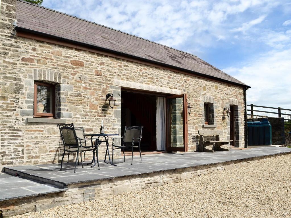 a brick building with a table and chairs on a patio at Bwthyn Y Bugail in Felindre