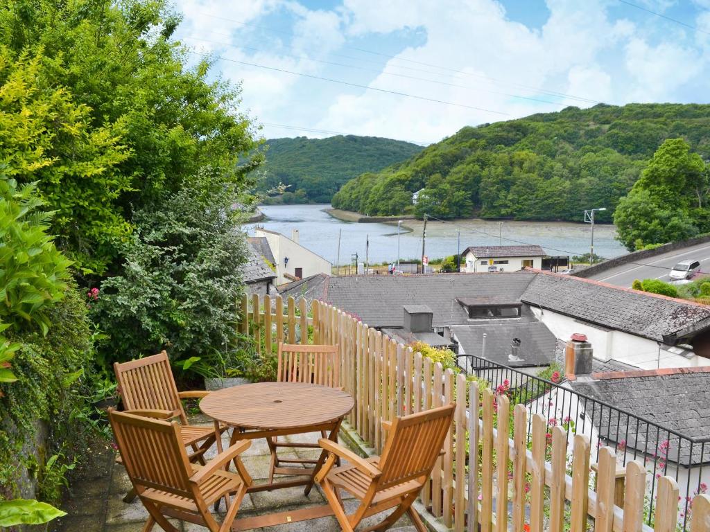 a table and chairs on a balcony with a view of a river at Watersmeet in Looe