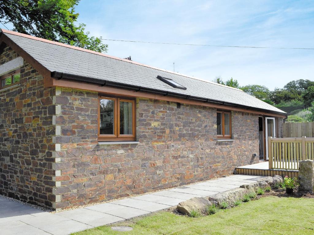 a brick house with a bench in front of it at Dairy Cottage in Bodmin