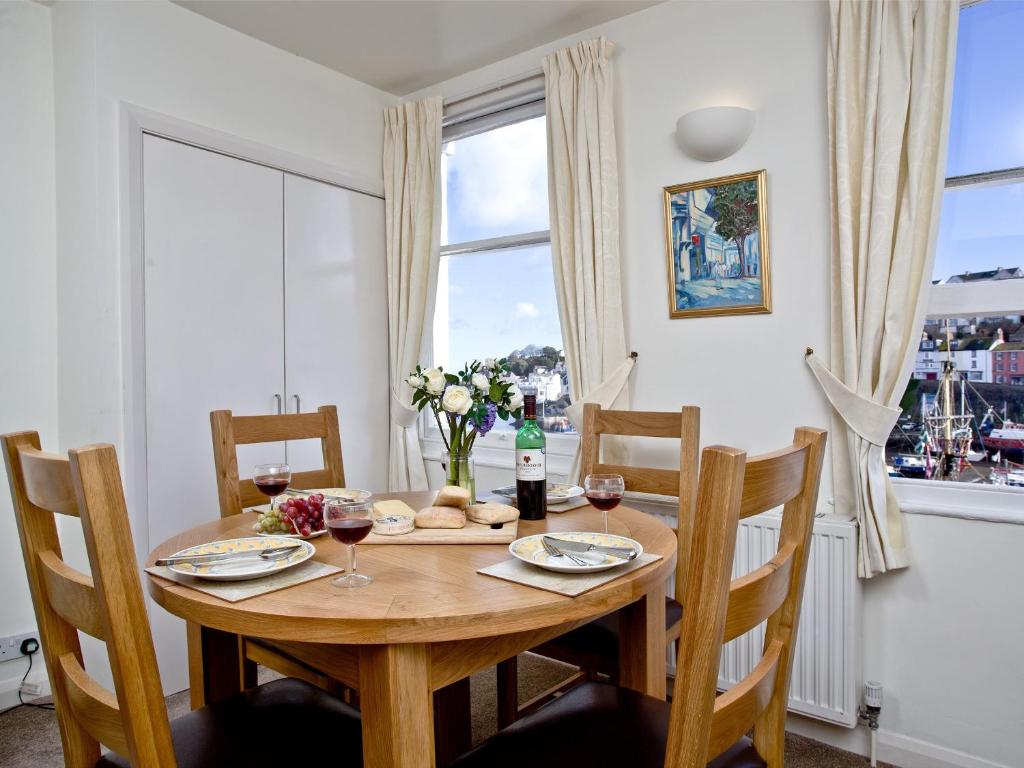 een eetkamer met een houten tafel en een raam bij 2 Fishermans Loft in Brixham