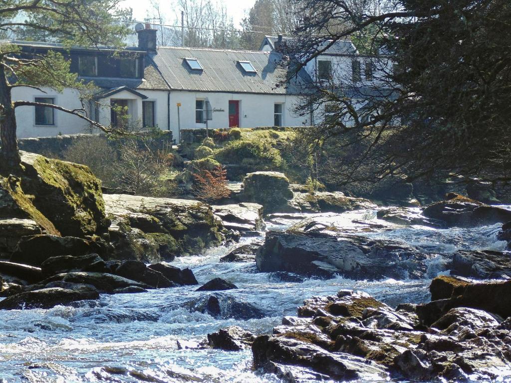 a river with rocks in front of a house at Gracedieu in Killin