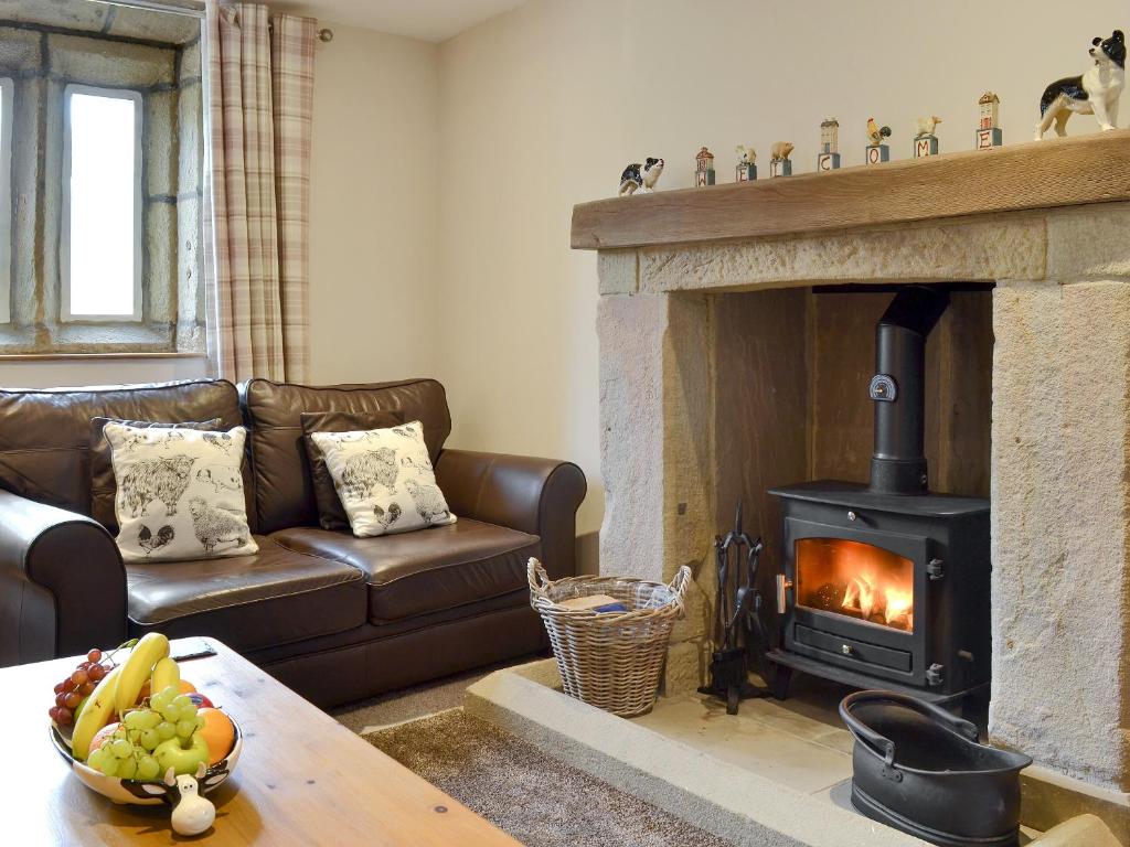 a living room with a couch and a fireplace at Little Grans Cottage in Cowling