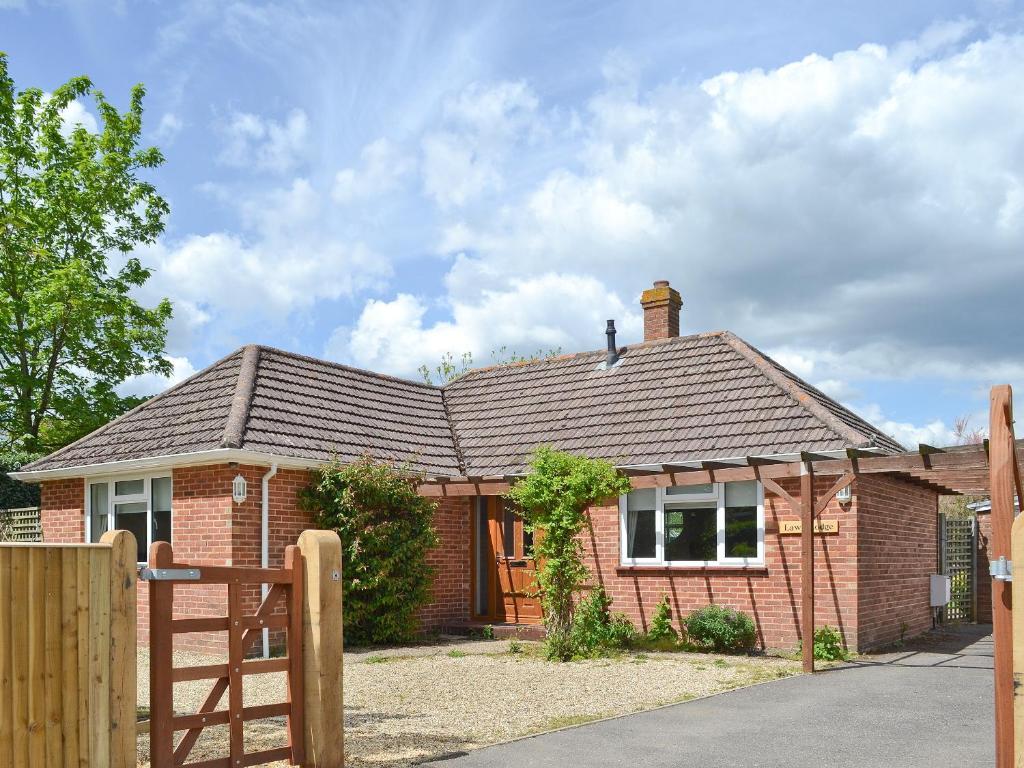 a brick house with a wooden fence in front of it at Lawn Lodge in Brockenhurst