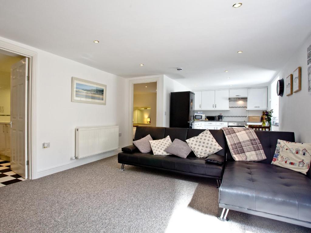 a living room with a black couch and a kitchen at Devon Villa Garden Apartment in Torquay