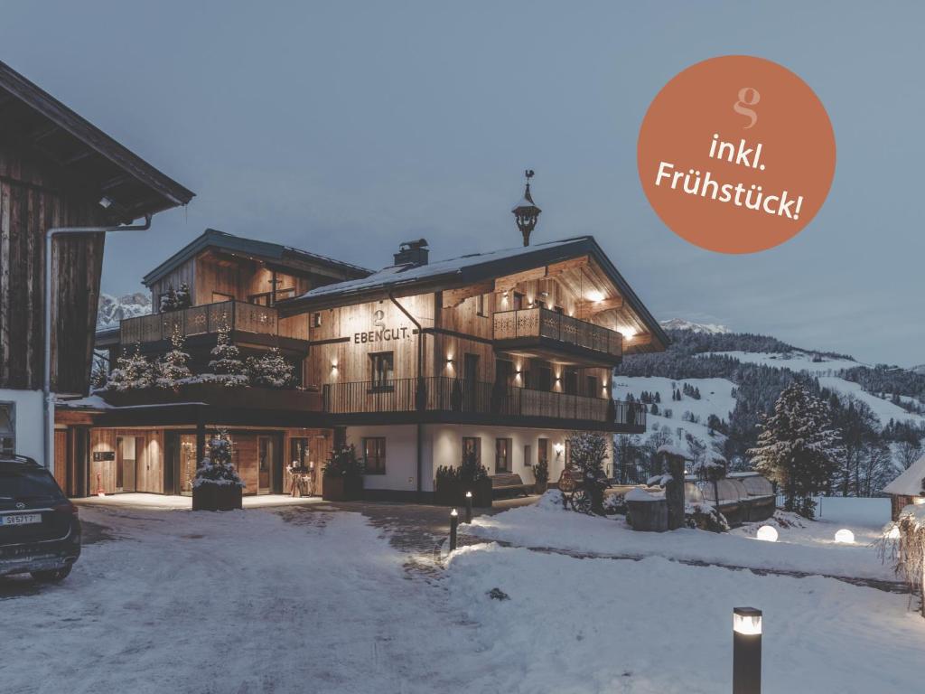 a large wooden building in the snow with the words innkritisk at Biohof Ebengut in Maria Alm am Steinernen Meer