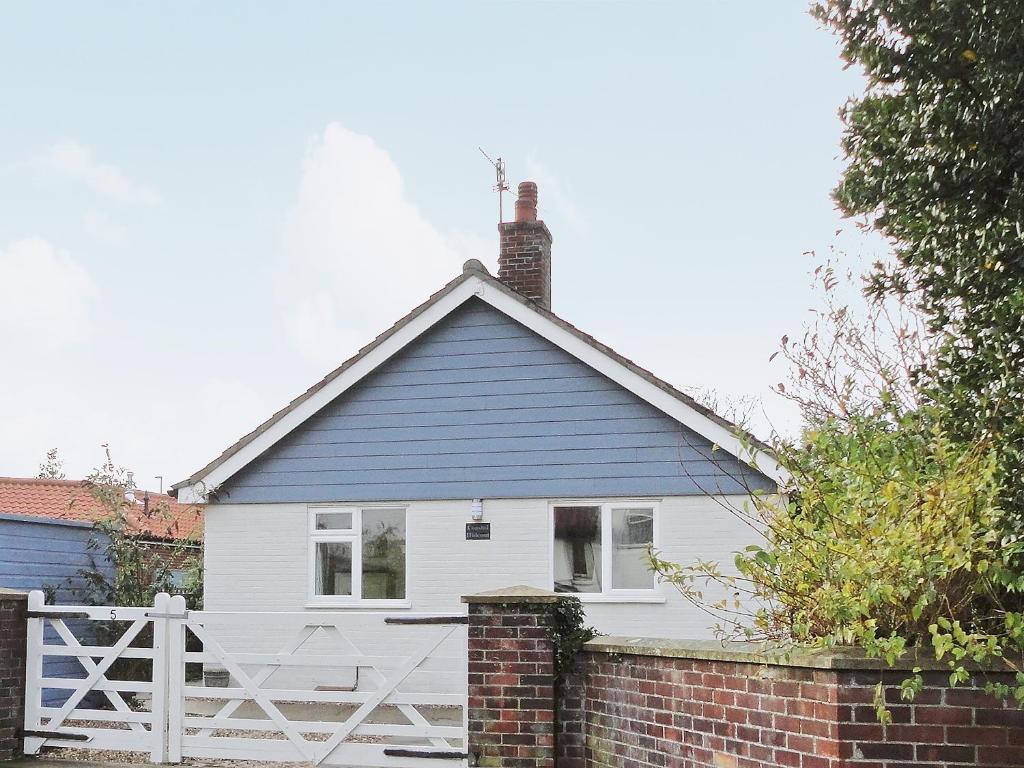 Casa blanca con techo azul y valla de ladrillo en Coastal Hideout, en Wells-next-the-Sea