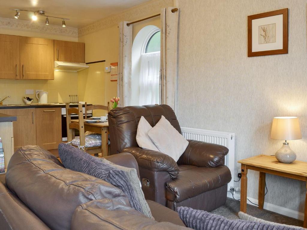 a living room with a leather couch and a table at Eldin Hall Cottage 1 - Uk2483 in Cayton