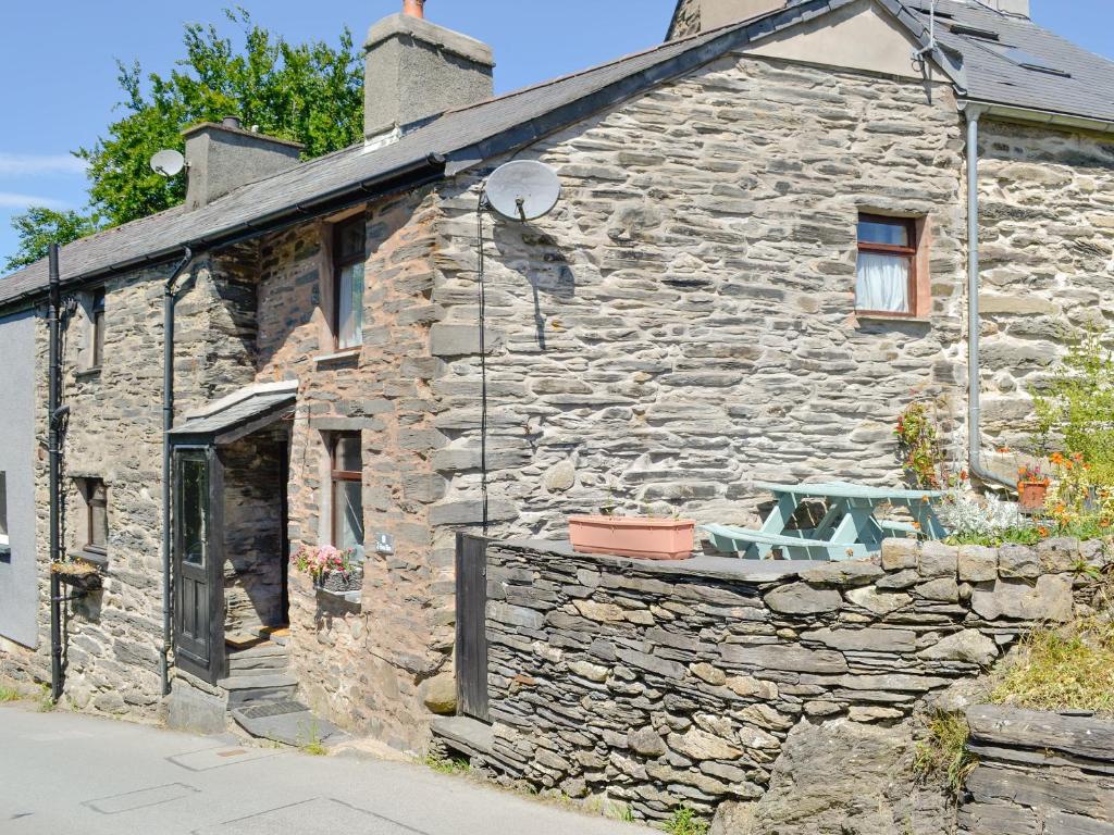 a stone house with a bench on the side of it at Bron Elan in Dolwyddelan