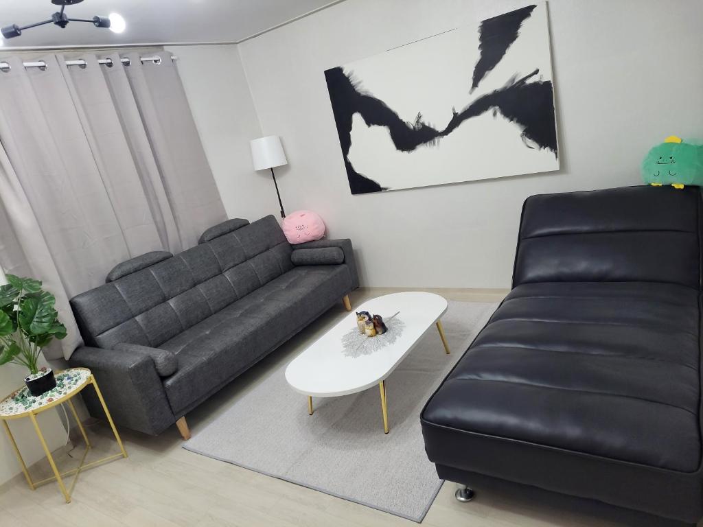 a living room with a black couch and a white table at On the main street of HBC in Seoul