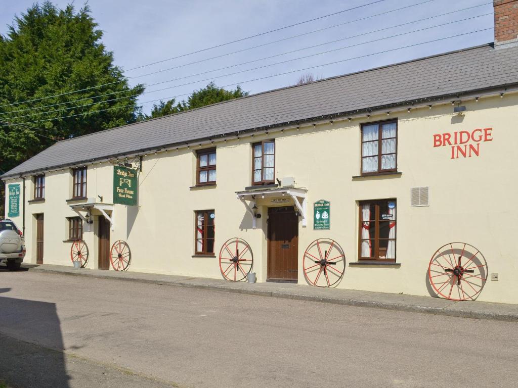 a building with wagon wheels on it on a street at The Bridge Inn Apartment in Bridgerule