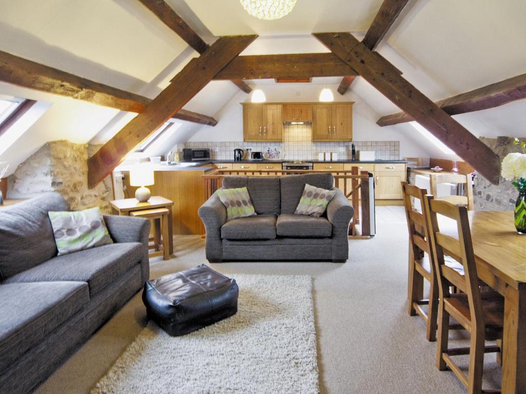 a living room with a couch and a table and a kitchen at Graianog Bach in Llanllyfni