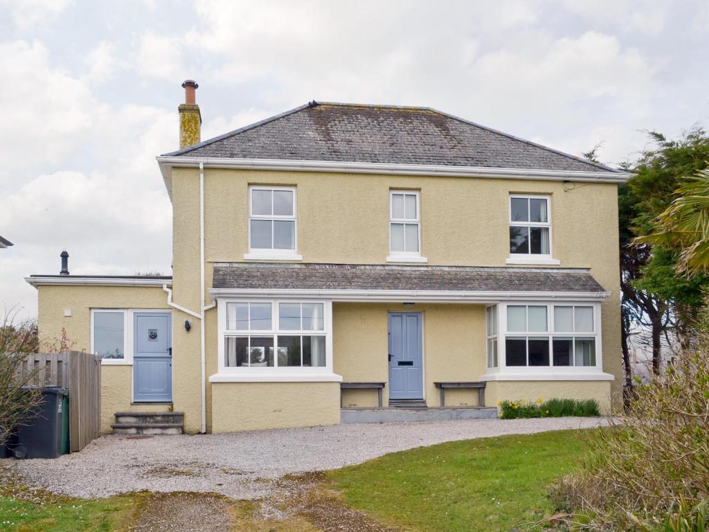 a yellow house with blue doors and a yard at Little Stretton in Bigbury on Sea