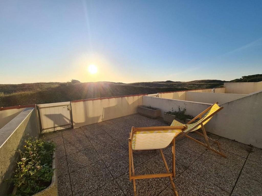 une chaise assise au-dessus du toit avec le coucher du soleil dans l'établissement Studio cabine 4 pers en bord de plage, véranda, terrasse ensoleillée - Saint-Jean-de-Monts - FR-1-224C-189, à Saint-Jean-de-Monts