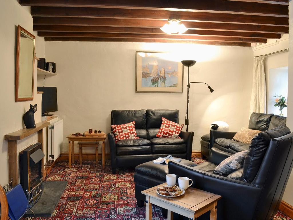 una sala de estar con 2 sofás de cuero y una mesa. en Yr Hen Sgubor en Pentre-briwnant