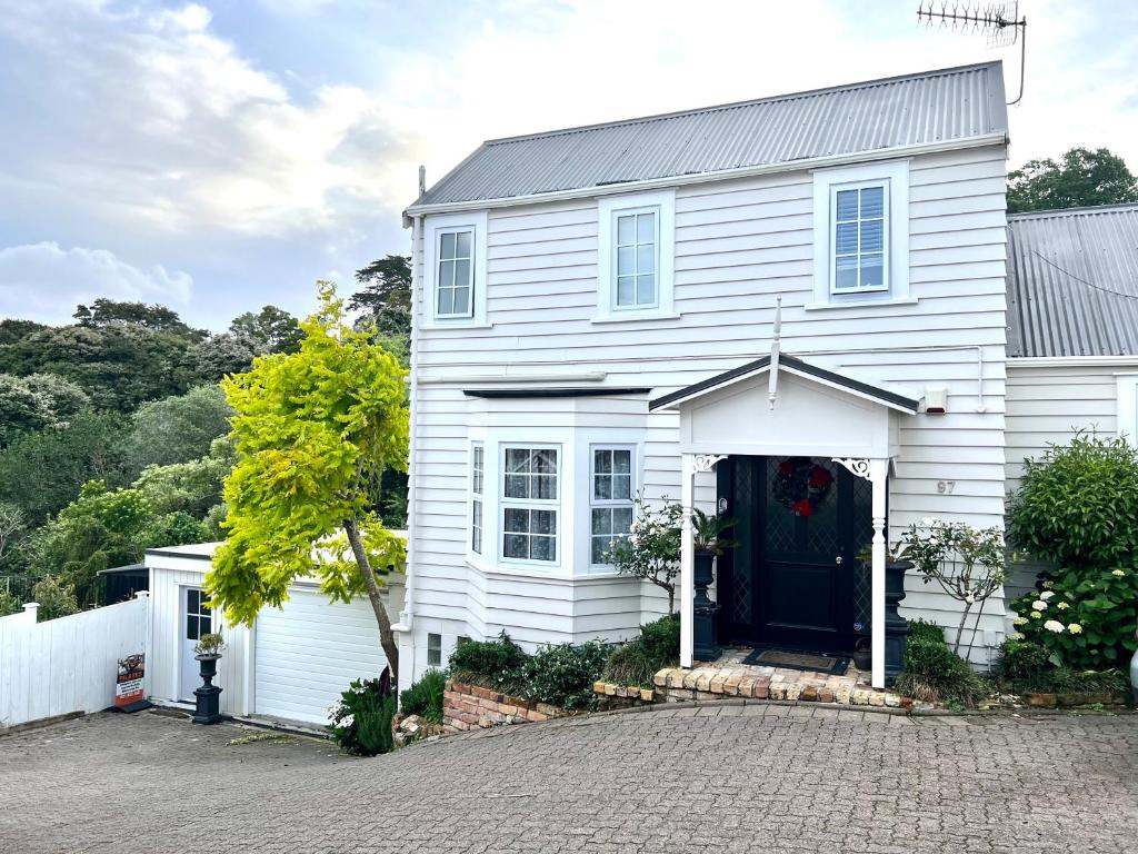 una casa bianca con una porta blu di Dove Cottage ad Auckland