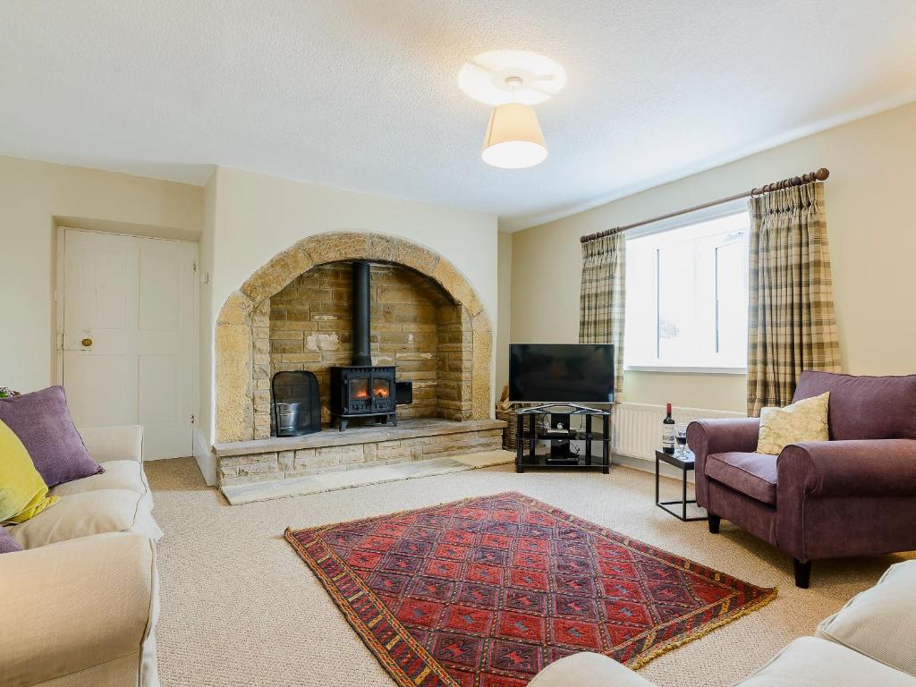 a living room with a fireplace and a tv at Backstone Bank Farmhouse in Wolsingham