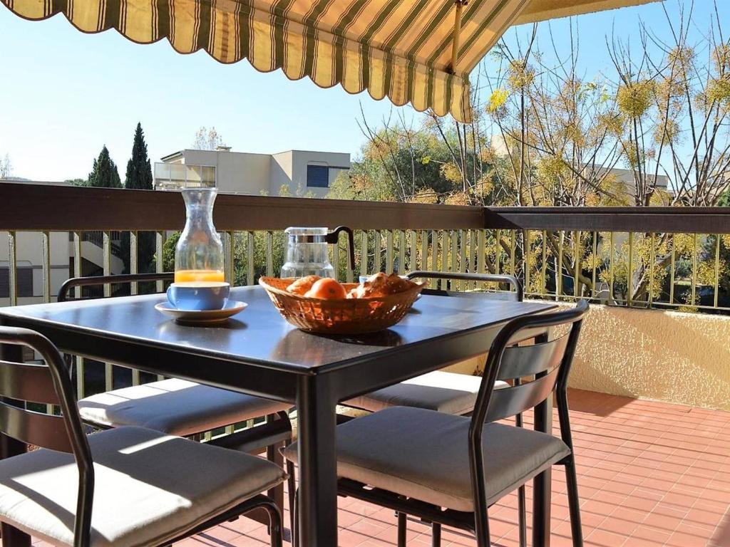 - une table avec des chaises et une corbeille de fruits sur la terrasse dans l'établissement Studio Calme avec Terrasse et Parking au Lavandou - 3 Couchages - FR-1-251-31, au Lavandou