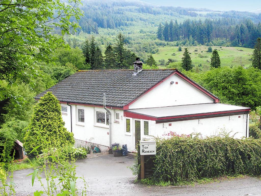 una pequeña casa blanca con un cartel delante en Tigh Raineach, en Strathyre