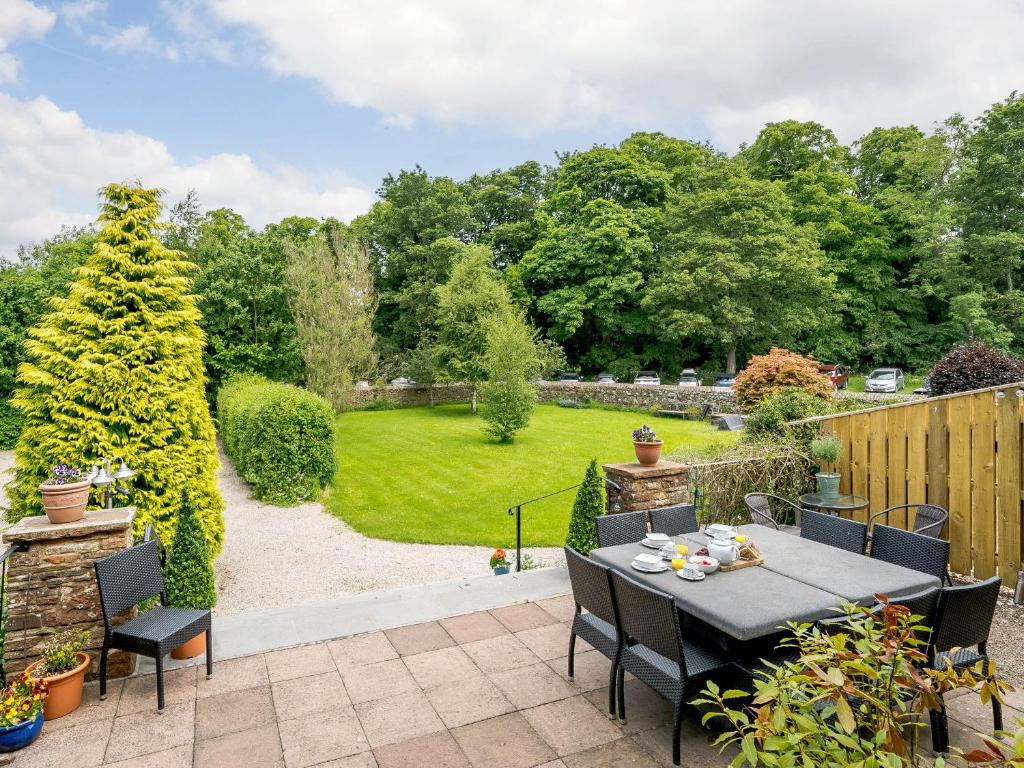 a patio with a table and chairs and a garden at Holly House in Pooley Bridge