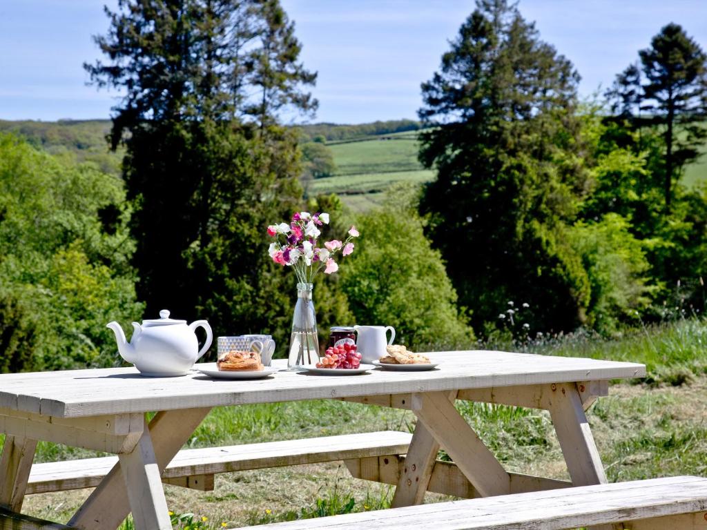 a picnic table with a tea pot and flowers on it at Blackbird Cottage in Kings Nympton