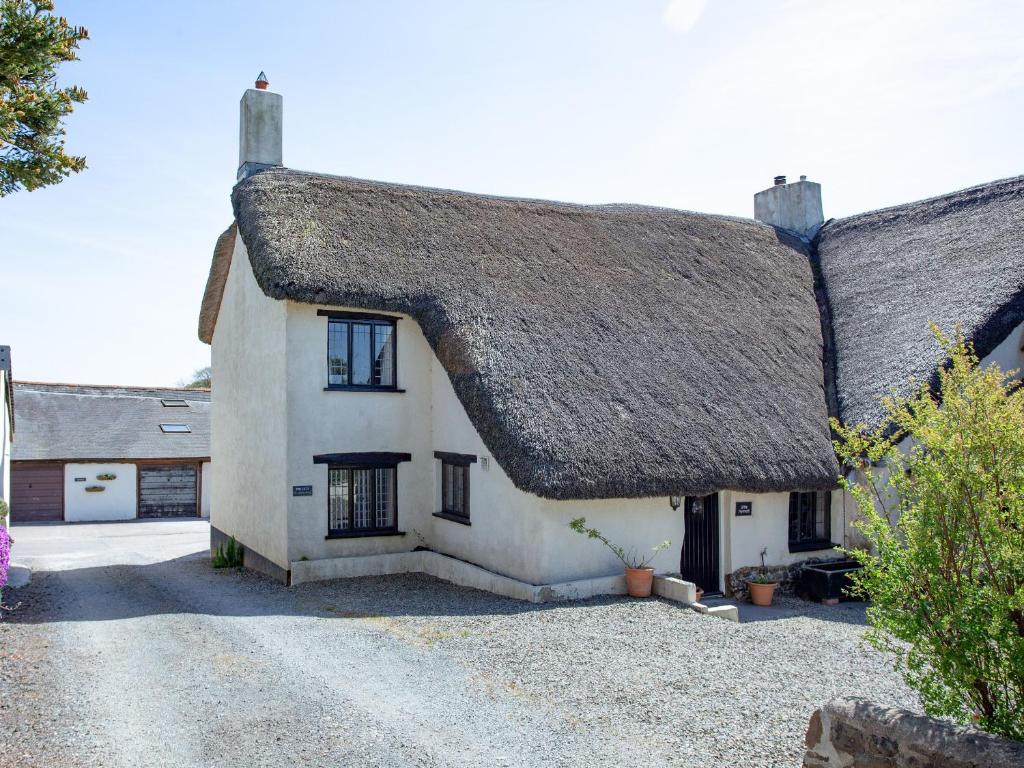 a large white house with a thatched roof at Little Nymett in North Tawton