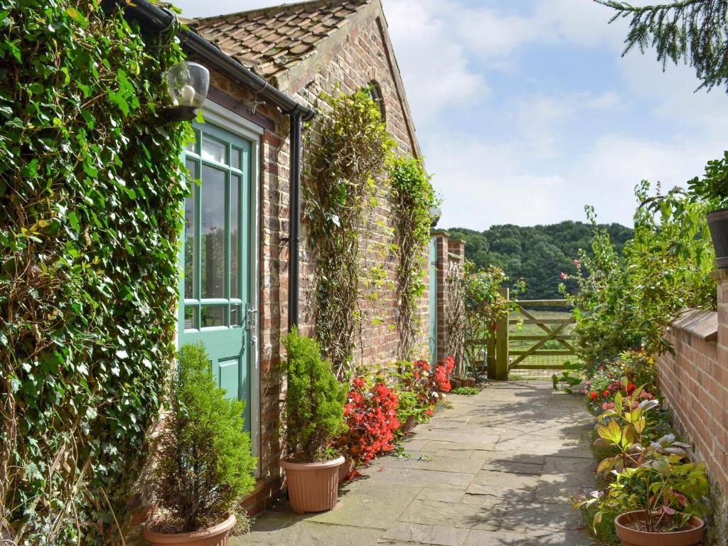 a brick house with a green door and plants at Rustys Cottage in Skirpenbeck