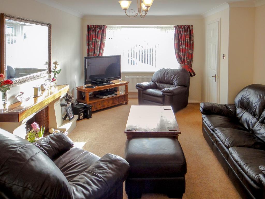 a living room with leather couches and a flat screen tv at 24 Steed Close in Goodrington