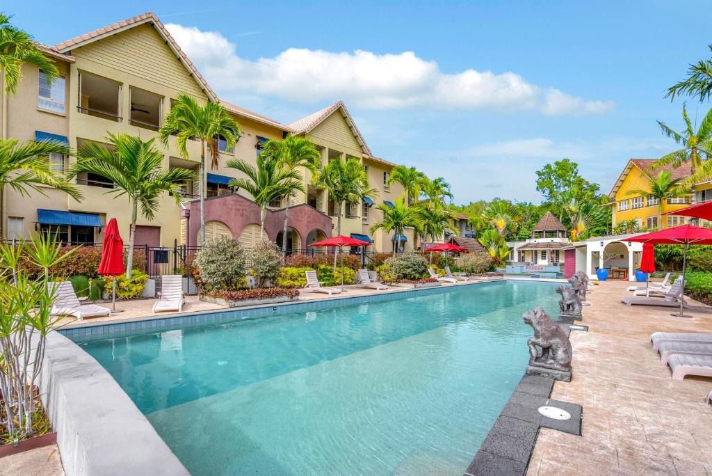 a pool at a resort with chairs and umbrellas at Vacanze A Casa - Resort Just Minutes From The CBD in Cairns North