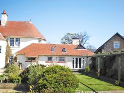 uma grande casa branca com um telhado vermelho em Tarandoun Cottage em Helensburgh