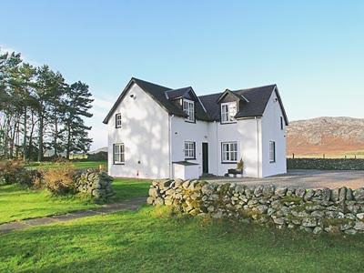 a large white house with a stone wall at Dhuallow in Aberarder