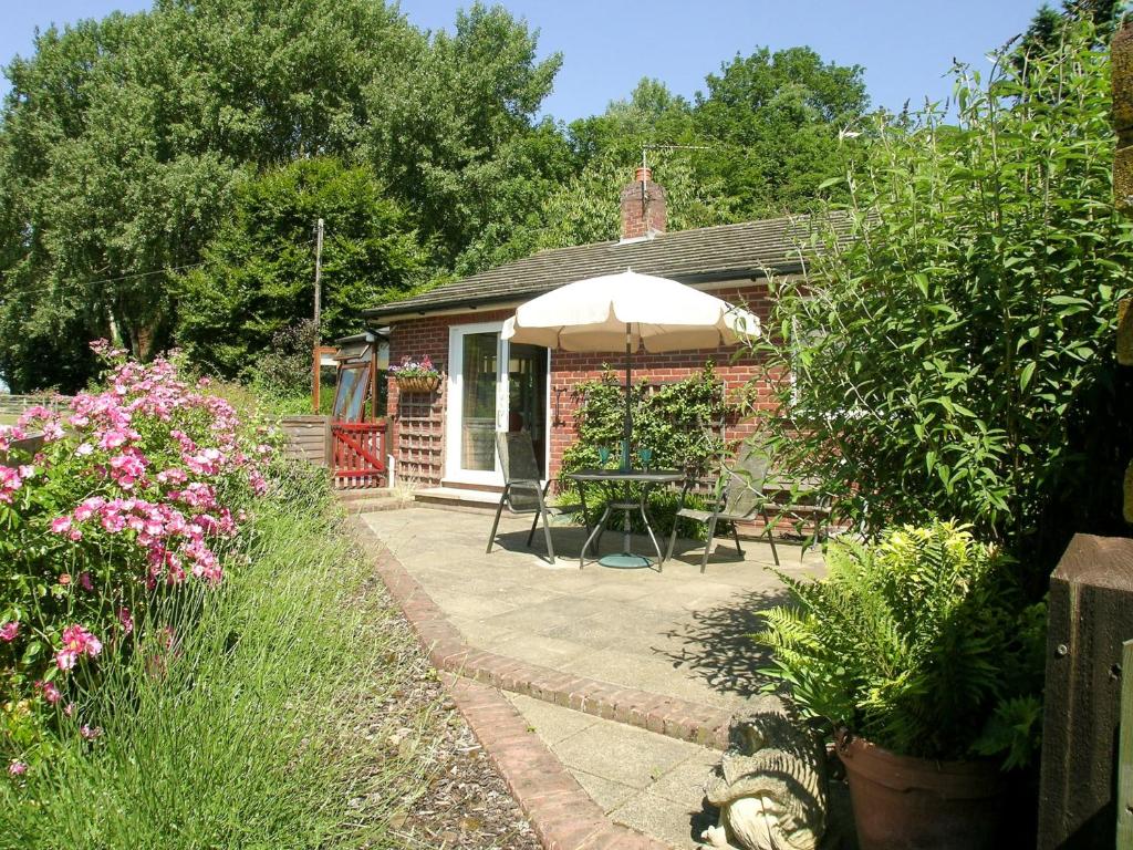 a brick cottage with an umbrella and a patio at Covert Cottage in Gasthorpe