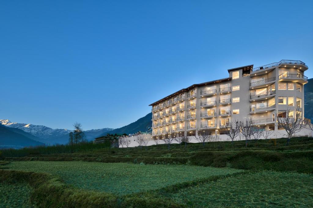 a building on a hill with mountains in the background at juSTa Grand View Resort & Spa, Manali in Manāli
