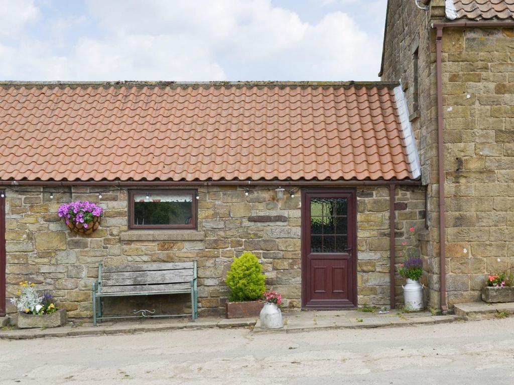 un edificio de piedra con banco y techo rojo en Trevena Star, en Rosedale Abbey