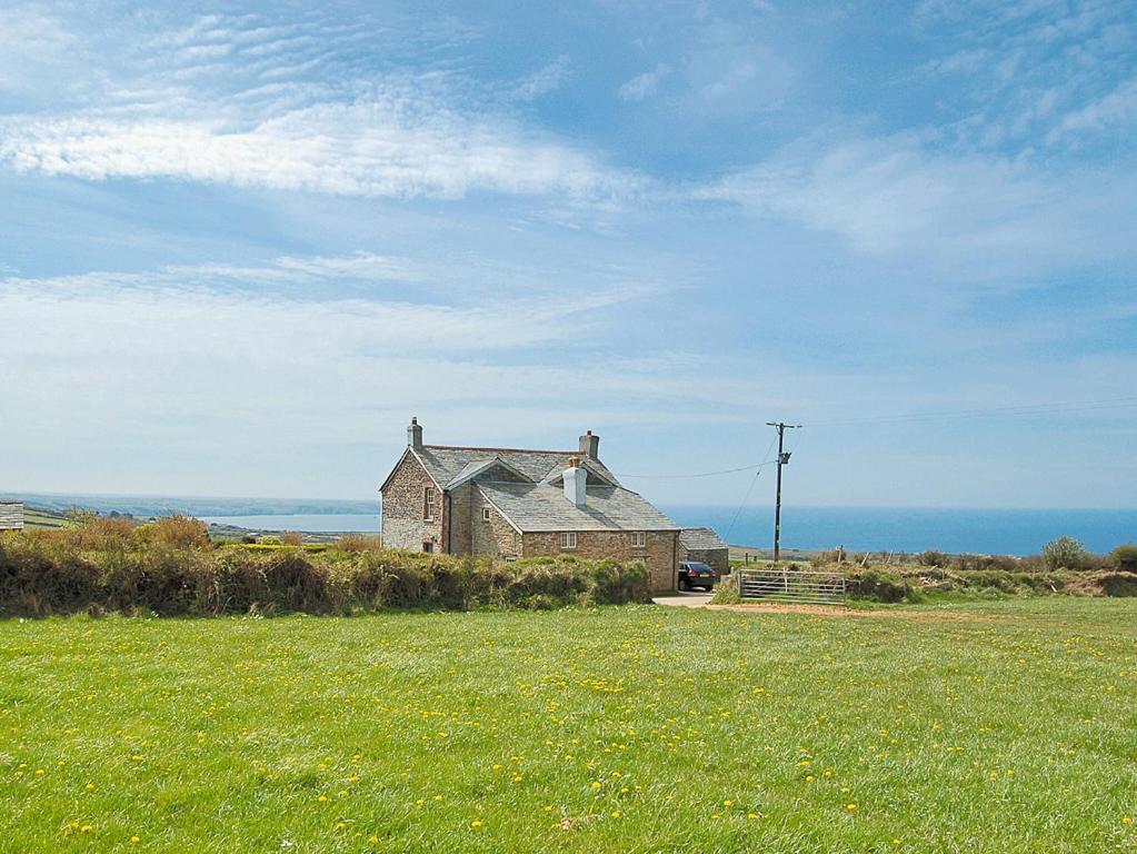 an old house sitting on top of a grass field at Downhouse Cottage in Delabole