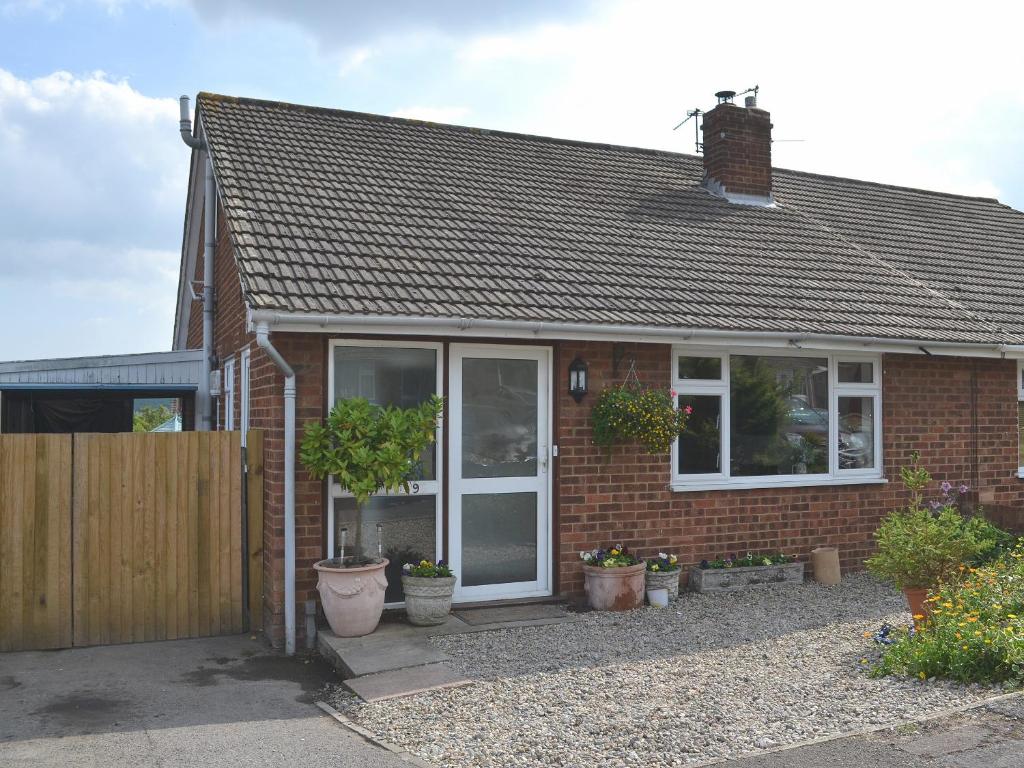 a red brick house with white windows and potted plants at Cedars in Fordwich