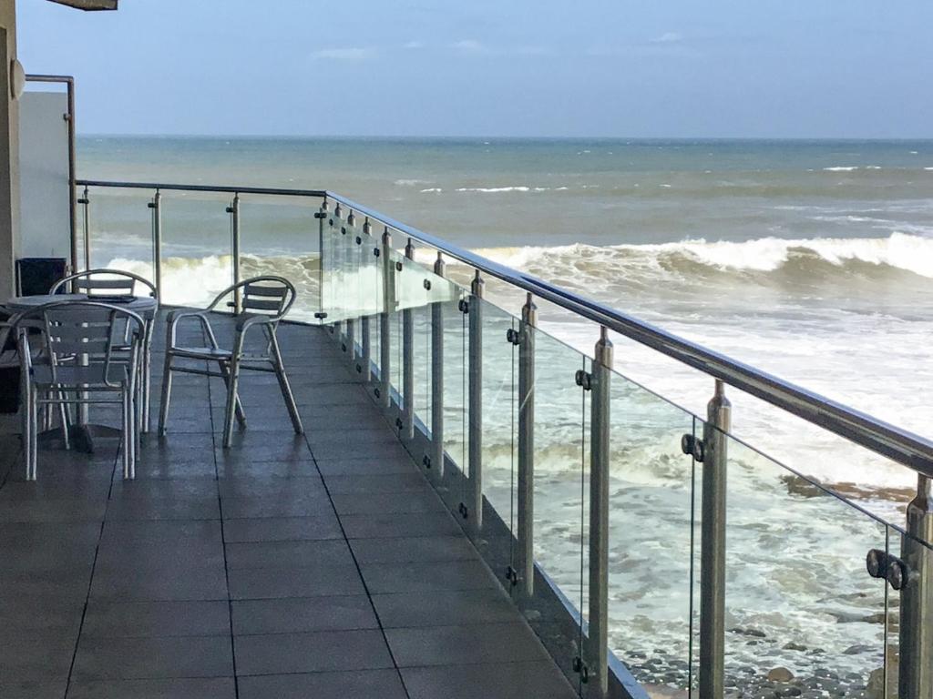 una mesa y sillas en un balcón con vistas al océano en Wow Westward Ho!, en Westward Ho