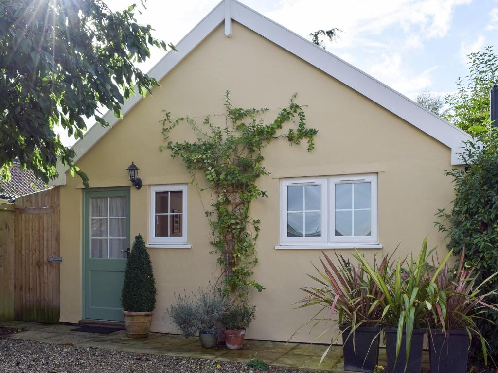 uma casa com uma porta verde e plantas em Field View Cottage em Bruisyard
