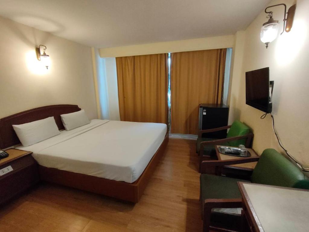 INTERTOWER HOTEL (SHA) في Sungai Kolok: غرفة نوم بسرير واريكة وتلفزيون