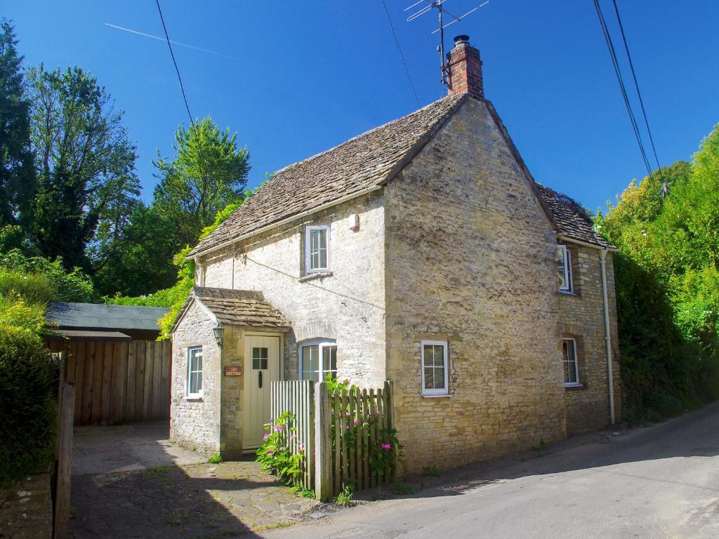 an old brick house with a gate and a fence at Ivy Cottage in Chedworth