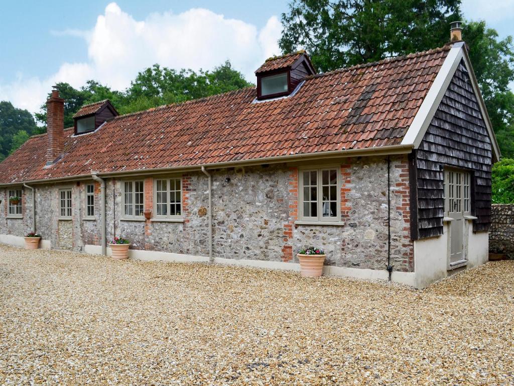 an old stone cottage with windows and a roof at Whatley Lodge in Winsham