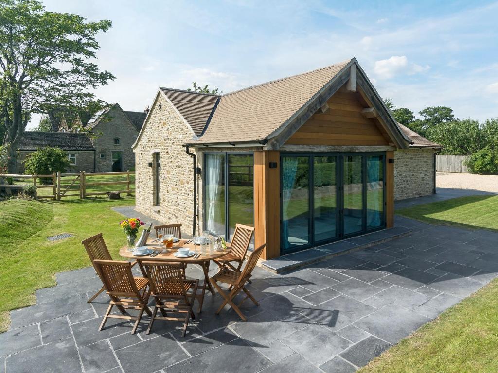 a patio with a table and chairs and a house at Puddledock Piggery in Berkley